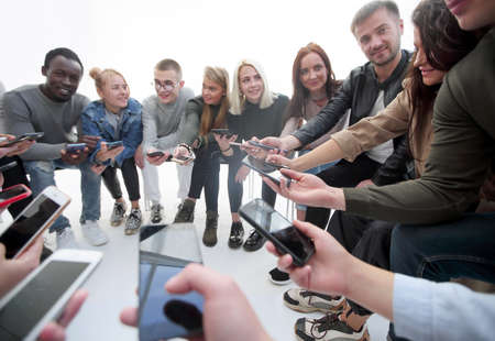 close up. groups of young people with smartphones sitting in a circle