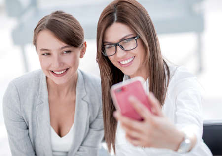 two business women taking selfies in the office