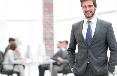 Handsome businessman smiling with his colleagues behindの写真素材
