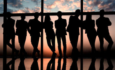 silhouette of a business team standing next to the office window