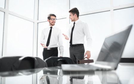 Two businessmen shaking hands standing at big windowの写真素材