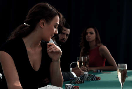 portrait of smiling woman with drink playing pokerの写真素材