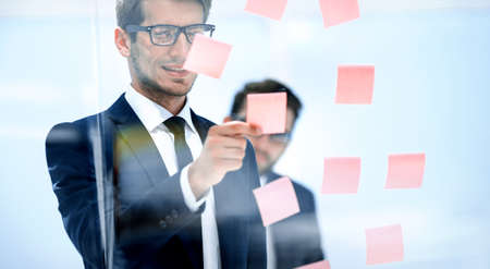 serious employee reads a sticker-note on the office Board.の写真素材