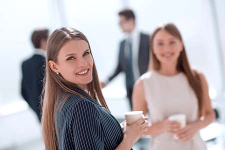 young businesswoman with a glass of coffee standing in the officeの写真素材