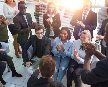 Office employees sit on chairs clap hands greeting presenter or speaker at group meeting close up.