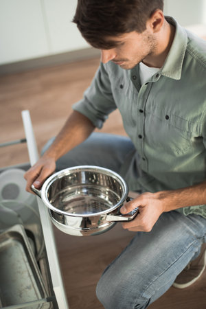 young man looking at clean dishes in dishwasher