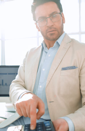 confident businessman pointing to calculatorの写真素材