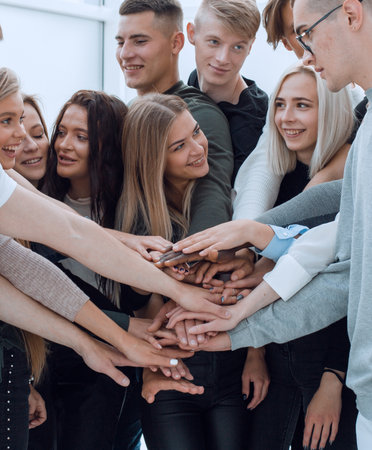 large group of young people joining their hands together.