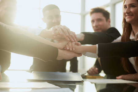 group of young business people joining their palms over a work Desk.