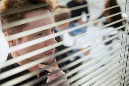 close up. young businessman looking through an office window.の写真素材