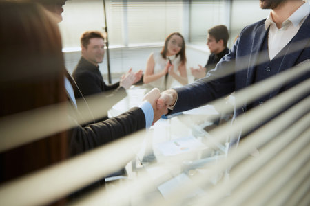 through the blinds. business partners greeting each other in the office .の写真素材