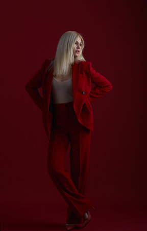 Fashion young woman in red suit. Red background.