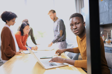 Portrait of a happy African American entrepreneur displaying computer laptop in office