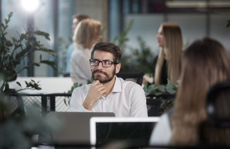A man is sitting at a desk with a laptop and a cup of coffee