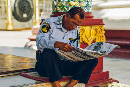 Yangon, Myanmar - FEB 19th 2014: Burmese male police are reading newspaper in front of temple at Shwedagon Pagodaのeditorial素材