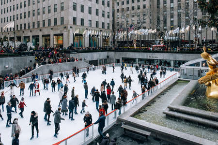New York City - USA - DEC 17 2018: Seasonal ice skating rink with a golden statue, in a famed complex with upscale shops & restaurants in Rockefeller Center  Midtown Manhattanのeditorial素材