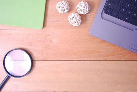 Wooden palette office desk table with laptop with smartphone, rattan ball, green notebook and magnifying glass. Top view with copy space, flat lay.の写真素材