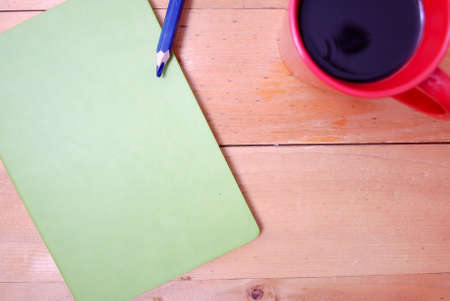 Wooden palette office desk table with coffee in red mug, rattan ball, green notebook and green notebook. Top view with copy space, flat lay.の写真素材