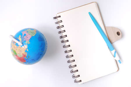 White office desk table with open note book, pen and globe. Top view with copy space, flat lay.の写真素材