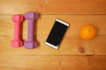 Flat lay of dumbbell, watch strap, heart rate belts, sport shoe, orange from top view. Sport equipments and fitness items concept.の写真素材