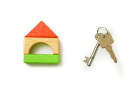Conceptual image of miniature home icon made from wood bricks and key on isolated white background