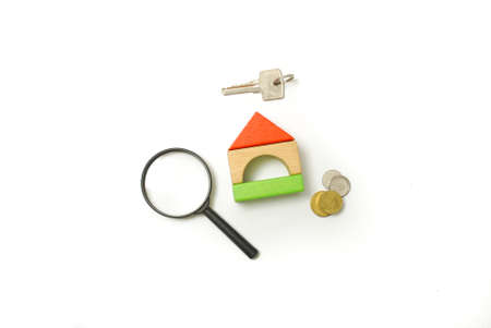 Conceptual image of miniature home icon made from wood bricks with key, coin and magnifying glass on...