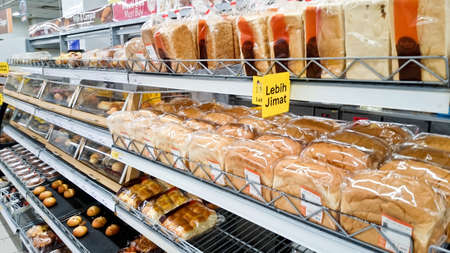 MELAKA, MALAYSIA - April 13, 2018 : Assorted type of cake, bread and bun on shelf rack display in the Tesco store.のeditorial素材