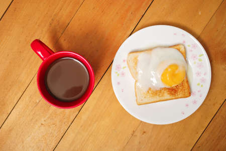 Toaster bread with half boiled egg topping in plate served with cup of coffee. Wooden background from top with copy spaceの写真素材
