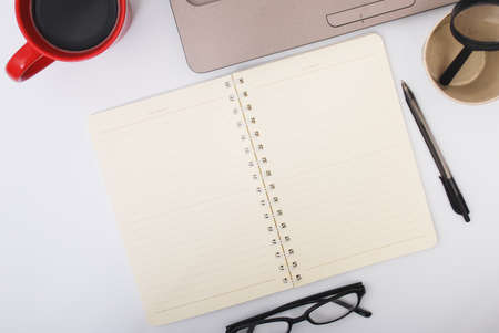 Stylish office table desk. Workspace with laptop, notebook, spectacle, pen, magnifying glass, cup of coffee on white background. Flat lay, top viewの写真素材