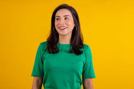 Studio shot of young woman in white shirt on yellow background with various facial expressions.の写真素材