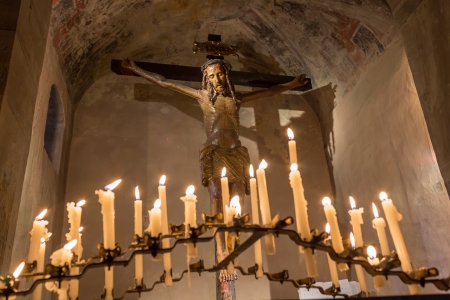 A Crucifix in a church in Italy surrounded with lighted candlesの写真素材