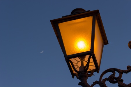 A lamp in the evening with a quarter moon in the Backgroundの写真素材