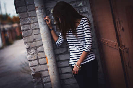 brunette girl in  t-shirt standing beside   garagesの写真素材