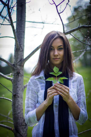 portrait of a cute girl in the forest with leafの写真素材