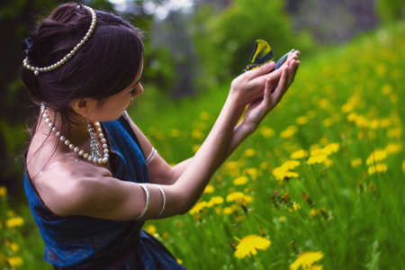 the girl in the dandelions holding a butterflyの写真素材