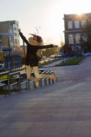 happy girl in coat jumping on the street