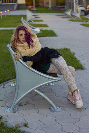 girl with colored hair coat sitting on the benchの写真素材