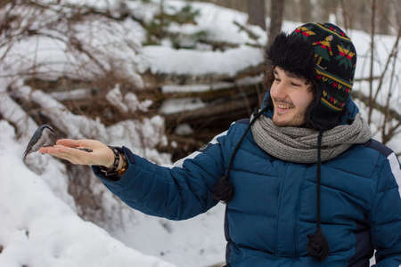 man feeding the bird with his hands in the woodsの写真素材