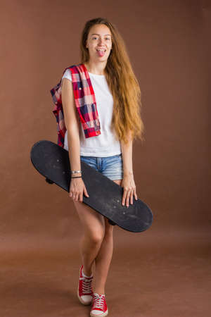 portrait of a cute girl with a skateboard in the Studioの写真素材