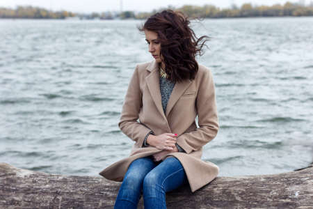 portrait of a sad girl sitting near the waterの写真素材