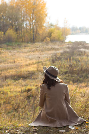 girl in a coat and hat sits and dreamsの写真素材