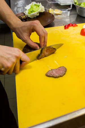 Chef cutting the meat on a wooden board