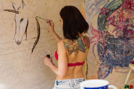 girl tattoo drawing on the wall with paintsの写真素材
