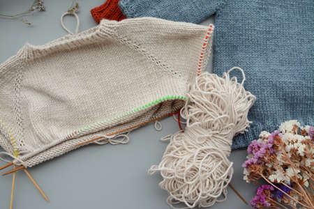 Various colors and sizes handmade baby sweaters, two items done and one in progressの写真素材