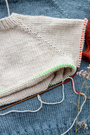 Various colors and sizes handmade baby sweaters, two items done and one in progressの写真素材