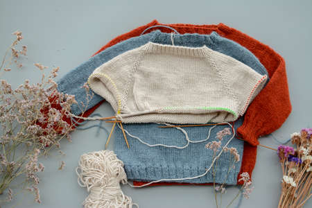 Various colors and sizes handmade baby sweaters, two items done and one in progressの写真素材