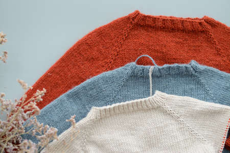 Various colors and sizes handmade baby sweaters, two items done and one in progressの写真素材