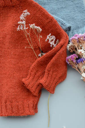 Various colors and sizes handmade baby sweaters, two items done and one in progressの写真素材