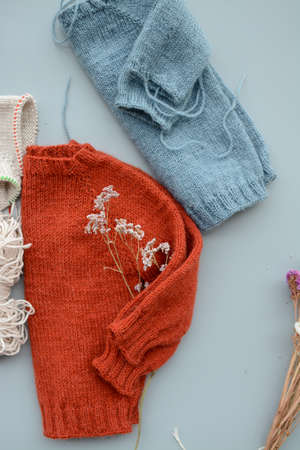Various colors and sizes handmade baby sweaters, two items done and one in progressの写真素材