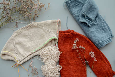 Various colors and sizes handmade baby sweaters, two items done and one in progressの写真素材